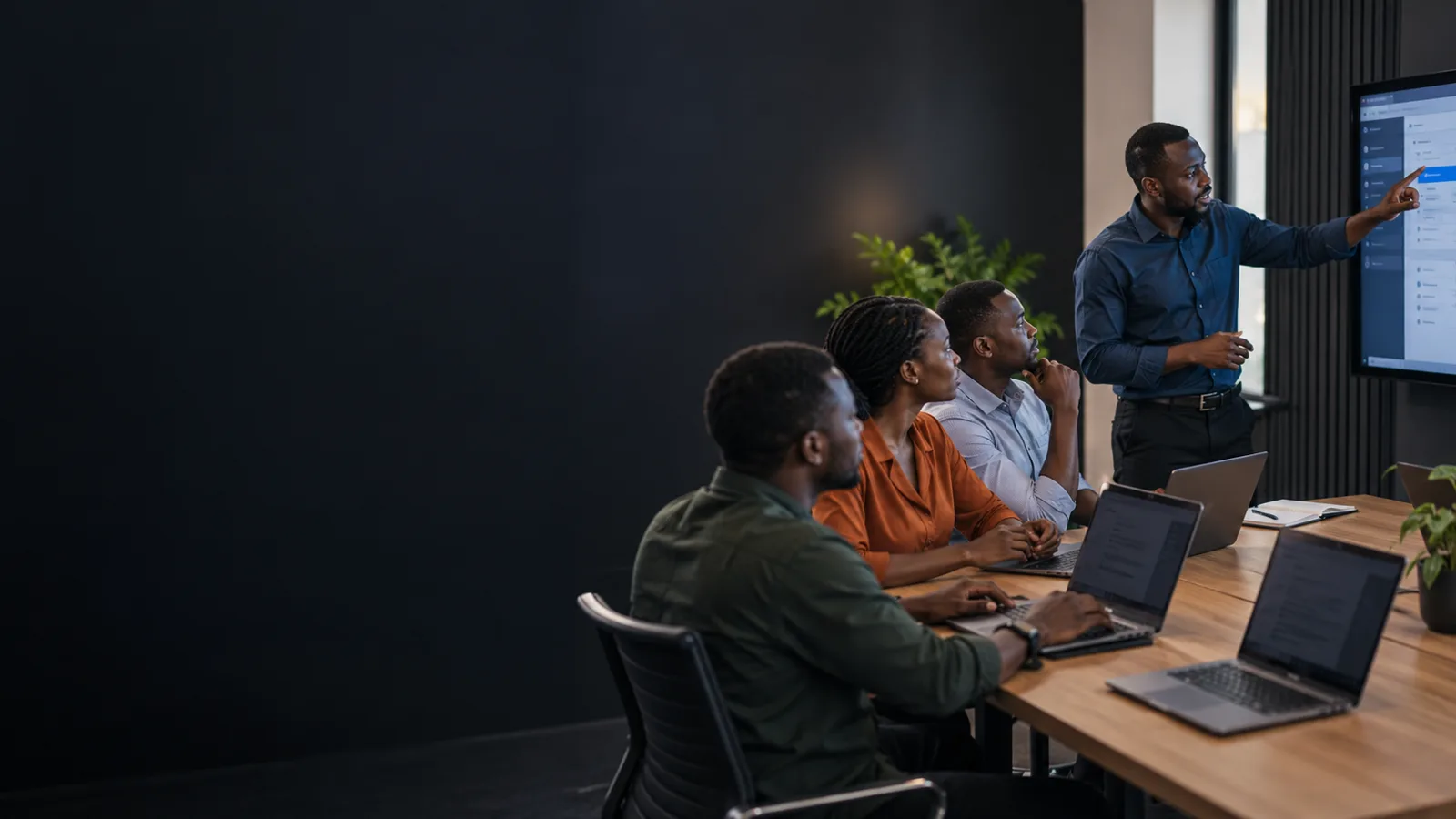 Black African instructor guiding adult staff through practical software training
