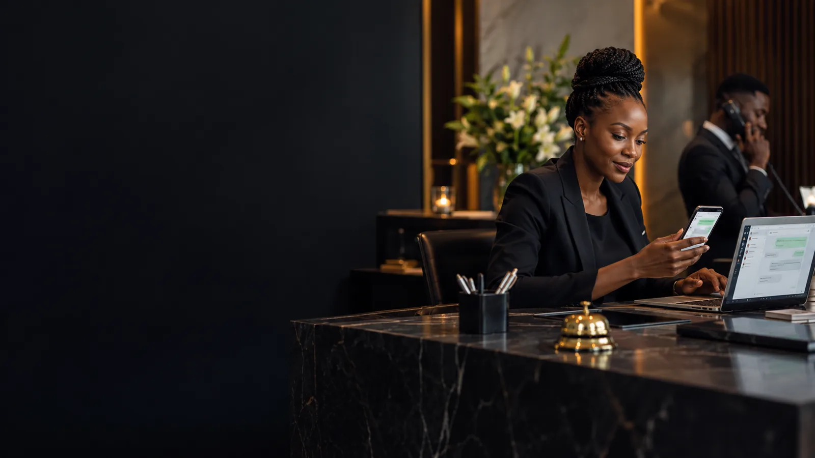 Black African business professional coordinating customer messages using a phone and laptop